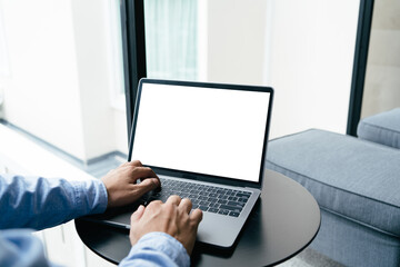 Close up view of man hands typing on keyboard of laptop computer on white desk at his home office. mockup laptop blank screen, clipping path.