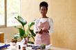 © ALTO IMAGES/Stocksy - Happy black woman showing bottle of handmade lotion