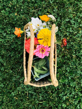 Basket Filled With Flowers And Vegetables Sitting On Green Grass
