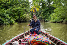 A Happy Fisherman Drives His Boat Through The Jungle