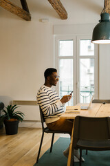 Smiling man using smartphone at the office
