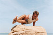 © Lucas Ottone/Stocksy - Man doing yoga on top of a rock