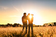 © kieferpix - Family of three father mother child standing in a field at sunset.