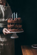 © Constance Ibanez/Stocksy - Chocolate layered birthday cake with blown candles