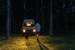 © Alba Vitta/Stocksy - Mand and dog walking in forest at night with camper van