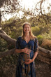 © Lucas Ottone/Stocksy - Pregnant woman smiling in nature