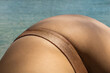 © Sonja Lekovic/Stocksy - body detail in golden bikini panties and blue sea in the background