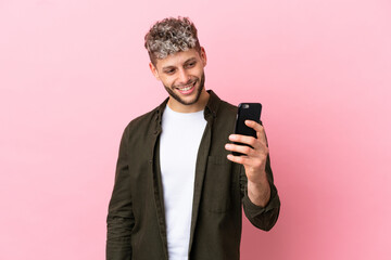 Wall Mural - Young handsome caucasian man isolated on pink background making a selfie