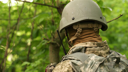 a portrait of a Ukrainian military man communicating by radio. a military man in the forest reports news on a walkie-talkie and gives orders. communication between units during a combat mission