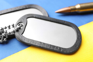 Wall Mural - Military ID tags and bullet on national flag of Ukraine, closeup