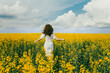 © Дарья Геращенко - A girl in a white dress and curly hair runs across a field of yellow flowers.