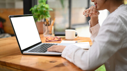 Cropped image of female employee using laptop computer on wooden office desk