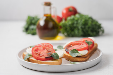 Wall Mural - Bruschetta with mozzarella, tomatoes and basil on plate, close-up view