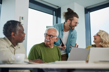 Young hipster educator teaching group of senior multiracial people using technology and the internet in the classroom.