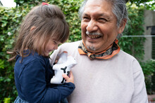 Smiling Senior Man With Granddaughter Outdoors