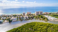 Aerial Drone View Of Bonita Springs Beach, Florida With The Bay And Mangroves In The Foreground And The Gulf Of Mexico In The Background 