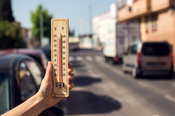 Fototapete - Hot weather. Thermometer in front of an urban scene during heatwave.
