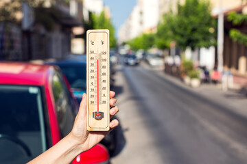 Fototapete - Hot weather. Thermometer in front of an urban scene during heatwave.