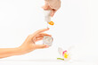 © shine - Close up woman hands holding glass jar of white face cream, pouring body care lotion on her finger and white orchid on white background. Organic cosmetics product Concept. Selective focus, Copy space