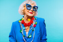 Portrait Of Smiling Senior Woman Wearing Sunglasses Against Blue Background