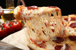 © New Africa - Woman taking slice of tasty pepperoni pizza at wooden table, closeup