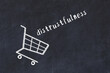 Chalk drawing of shopping cart and word distrustfulness on black chalboard. Concept of globalization and mass consuming