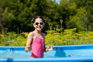 Portrait of a cheerful pretty teenage girl close-up in the pool against the background of the garden