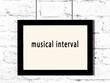 Black frame hanging on white brick wall with inscription musical interval