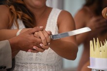 Closeup Shot Of A Groom And A Bride Cutting The Wedding Cake With A Knife