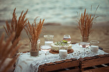 Picnic In The Evening At Sunset On The Sandy Shore Of The Sea Or Ocean. Decor In Boho And Rustic Style.