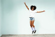 © neonshot - Happy young hipster woman with afro hairstyle and fashionable clothes jumping with big smile.  Sunny summer day.