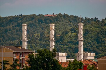 Tall towers at the foot of the forested hills in Chivasso, Italy