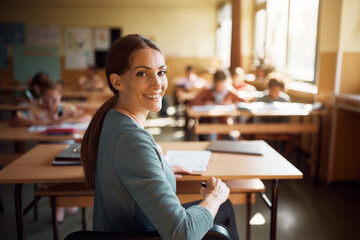 Happy female teacher in classroom looking at camera.