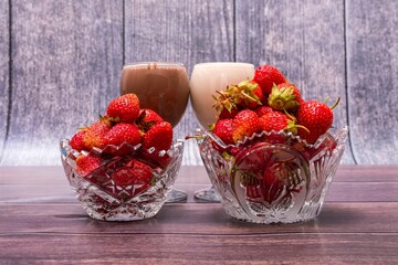 Canvas Print - Three crystal vases with ripe red strawberries and two glasses of cocktails stand on wooden table.