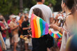 © Dina - Rainbow flag symbol of Pride at public event. Unrecognizable people in the crowd with rainbow flags. Demonstration and protest. Lgbtq queer rights.