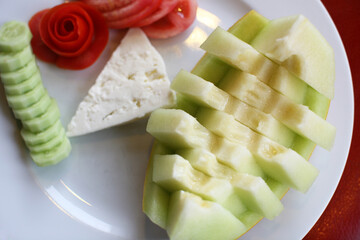 Wall Mural - Yellow melon, cucumbers, tomatoes and white cheese in the dinner plate.