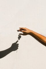 two hands making love heart shadow symbol on the sand at the wall.