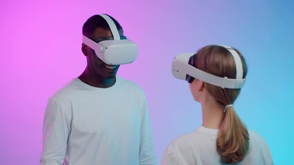 Poster - Multiethnic couple play virtual reality simulation in goggles isolated over neon background.