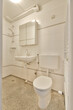 Wall hung toilet and small sink in corner in lavatory room with beige tile