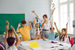 © Studio Romantic - Happy teacher and children having fun in class. Cheerful woman and joyful students play games in the classroom, write in notebooks, answer questions and solve problems together. Back to school concept
