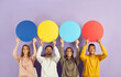 © Studio Romantic - Different happy cheerful positive young multiethnic people sharing their points of view holding round colourful red, blue and yellow mock up speech bubble banners. Studio portrait on purple background