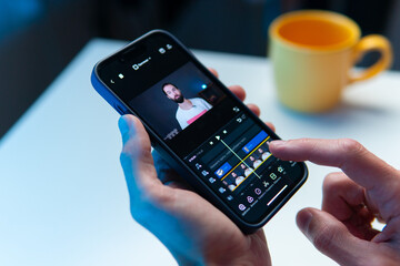 the video editor program on the phone. a young man is editing a video on his phone