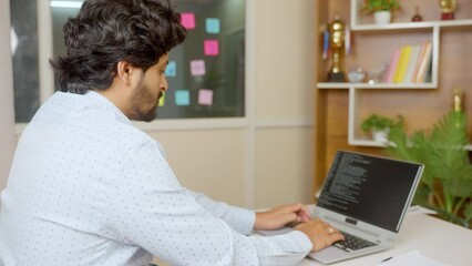 Side view of Corporate IT employe coding on laptop at office - concept of white collar jobs, software geek and freelance worker.