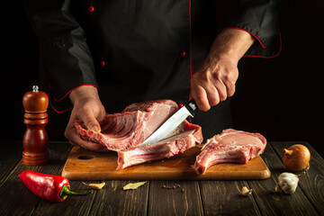 Chef cuts raw ribs on a cutting board before barbecuing. European cuisine. Cooking delicious food in the hotel kitchen