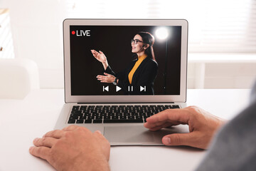Wall Mural - Man watching performance of motivational speaker on laptop at white table, closeup