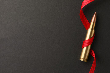 Wall Mural - Bullet and red ribbon on black background, top view. Space for text