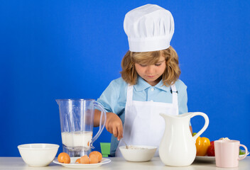 Child chef isolated on blue. Funny little kid chef cook wearing uniform cook cap and apron cooked food in the kitchen.