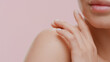 © pavel_dp - Extreme close-up shot of young slim good-looking white-skinned female model strokes her naked shoulder on pale pink background | Soft skin concept