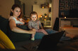 © Miljan Živković - Small caucasian child little girl toddler mother and daughter sitting in dark room at night at home on sofa bed watching cartoons or movies on laptop computer real people family growing up copy space