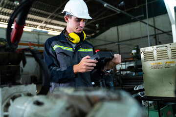 Wall Mural - Young factory worker working with adept robotic arm in a workshop . Industry robot programming software for automated manufacturing technology .